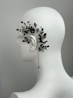 a white mannequin headpiece with black beads and leaves