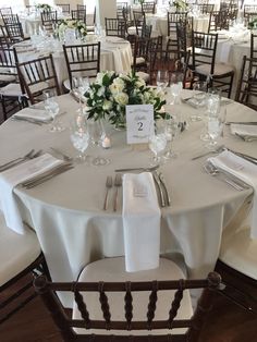 the table is set with white linens and silverware for an elegant wedding reception