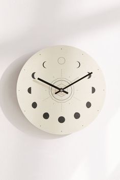 a white clock with black dots on the face and an arrow pointing to the moon