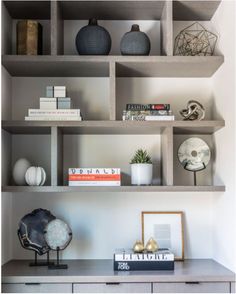 a shelf with books and vases on it next to other items in a room