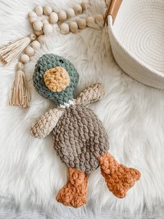 a crocheted duck laying on top of a white rug