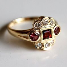 A semi-circle of diamonds totaling 0.25 carats flanks ruby-red garnets. Surely a heirloom piece to be cherished for generations. Ring size ranges from 5-8. Victorian Gold Ring, Antique Style Jewelry, Indian Wedding Jewelry Sets, Garnet And Diamond Ring, Heirloom Jewelry, Replica Jewelry, Victorian Gold, St Nicholas, Garnet Jewelry