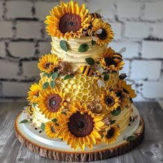 a three tiered cake with sunflowers and bees on the top is sitting on a wooden table