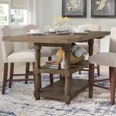 a dining room table with chairs and a rug in front of the table is decorated with flowers