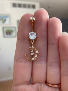 a person is holding a gold belly ring with a crescent and star design on it