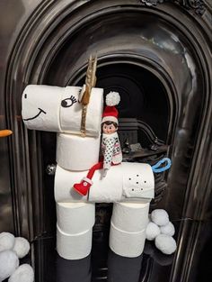 a white horse made out of toilet paper sitting in front of a fire place with balls on the floor