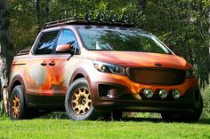 an orange and black suv parked in the grass next to some trees with yellow rims