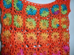 an orange crocheted top with multicolored flowers