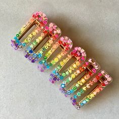 Handmade 2 part epoxy resin hair clips made by a real hairstylist! Rainbow pattern with carefully selected characters placed 1 at a time with clear glitter and completed with a gold clip backing that fits snug and securely in hair! 2 clips in each set! Great for girls gift but also for adults! Please note there may be slight imperfections or bubbles due to these being handmade Resin Hair Clips Ideas, Rainbow Hair Clips, Resin Hairclip Ideas, How To Make Resin Hair Clips, Hair Clip Resin, Resin Clips, Resin Hair Clips, Rainbow Accessories, Pony Bead Bracelets