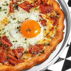 an egg and bacon pizza on a plate