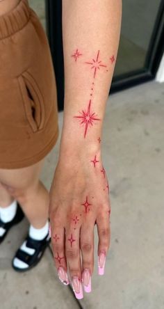 a woman's hand with red stars on it and pink nail polish, holding onto her arm