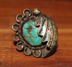 This ring in found condition shows its history and life in the patina and wear. North the cracked and chipped stone, most likely turquoise, and the dirt and patina of the metal, most likely silver. The ring features an oval cabochon green stone framed with a partial circle of small horseshoes and a feather partially folded over one half of the stone. The ring is unmarked and the materials are assumed to be turquoise and silver, but this is not guaranteed. Likewise, the ring is culturally attribu Antique Turquoise Ring With Patina, Antique Silver Turquoise Ring With Patina, Rustic Silver Rings With Patina, Vintage Turquoise Concho Ring, Vintage Adjustable Engraved Turquoise Ring, Jewelry Turquoise, One Half, Vintage Pieces, Green Stone