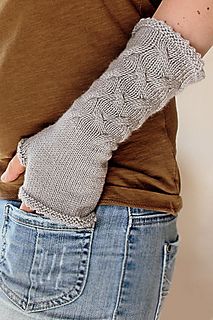 a woman wearing a pair of knitted fingerless mitts on her left arm