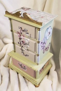 three drawers stacked on top of each other with flowers and butterflies painted on the sides