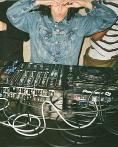 a man standing next to a dj set with headphones on his ears and hands over his face