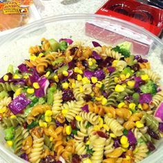 a bowl full of pasta salad with corn and broccoli on the side, ready to be eaten