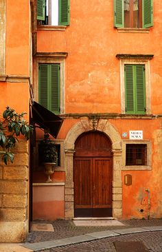 an orange building with green shutters on the windows