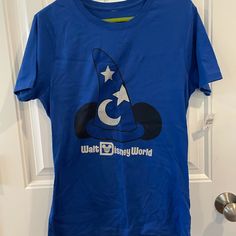 Brand New Never Worn. Size Medium Blue Short Sleeve Themed Tops, Blue Disney T-shirt For Disney Trips, Disney Blue Pre-shrunk Tops, Blue Disney Tops For Disney Trips, Blue Disney Style Tops For Disney Trips, Disney Graphic Print Blue Shirt, Blue Mickey Mouse Short Sleeve Tops, Blue Short Sleeve Tops With Mickey Mouse, Blue Short Sleeve Themed Shirt