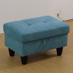 a blue ottoman sitting on top of a hard wood floor next to a white wall