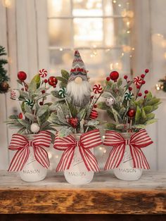 three glass vases filled with christmas decorations