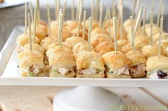 there are many small appetizers on the white platter with toothpicks in them