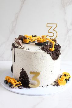 a birthday cake with construction trucks on top and the number three is decorated in white frosting