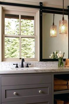 a bathroom sink under a large mirror next to a window with two lights on it