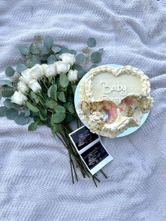 there is a cake and flowers on the bed with it's name written in frosting