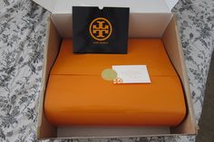 an orange chair sitting on top of a bed next to a white box with a black bag