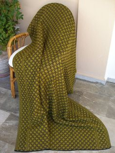 a chair covered in a blanket sitting on the floor next to a potted plant