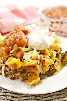 a white plate topped with food next to a bowl filled with sauce and sour cream