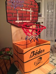 an orange box with a basketball in it on top of a table next to a brick wall