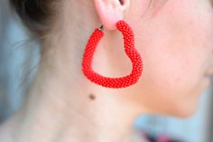 a close up of a person wearing red beaded earring designs on their ears