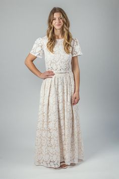 a woman wearing a white dress with short sleeves and an open back, posing for the camera