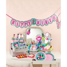 a birthday party set up with pink and blue decorations on a white table in front of a mirror