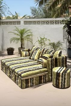 a large couch sitting on top of a patio next to a potted palm tree