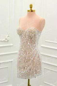 a mannequin wearing a dress made out of sequins and beads is shown in front of a white wall