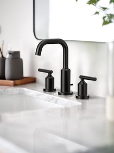 two black faucets sitting on top of a white counter next to a mirror