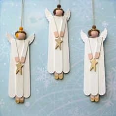 three angel ornaments hanging on the wall with gold stars and bells in front of them