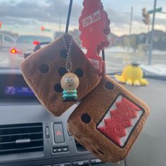 two stuffed animals hanging from the dashboard of a car