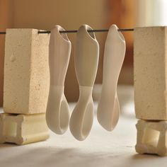 three white vases are hanging on a clothes line with two blocks in the background