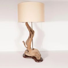 a table lamp made out of driftwood with a white shade on it's base