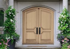 a large wooden door in front of some flowers