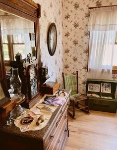 an old fashioned dresser and mirror in a room with floral wallpaper on the walls