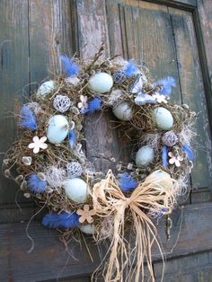 a wreath with blue and white ornaments hanging on a wooden door, decorated with grass