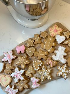 a wooden board topped with lots of cut out cookies