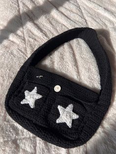 a crocheted purse with white stars on the front and black bottom, sitting on a bed