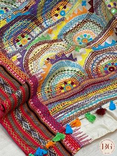 a multicolored blanket with tassels and beads on the edges is laying on a white surface