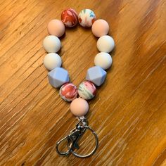 a bracelet with several different colored beads and a metal hook on a wooden table top