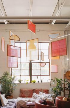 a living room filled with lots of furniture next to a large window and potted plants